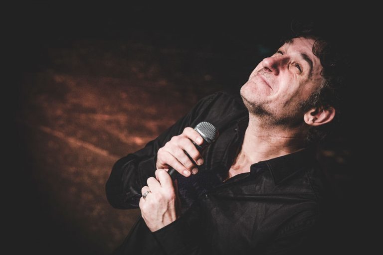 Tom Stade with eyes closed, holding the microphone