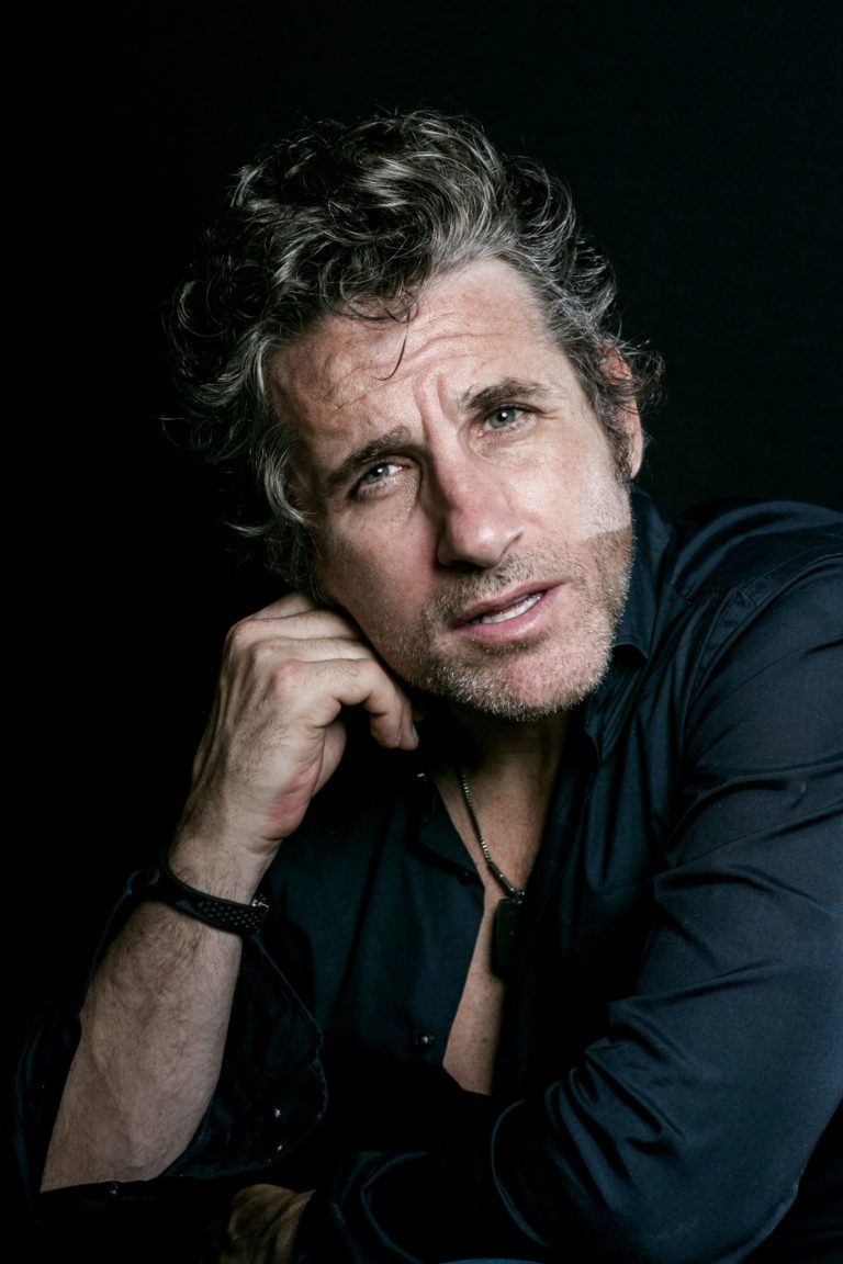 Tom Stade portrait in a black shirt, hand to chin