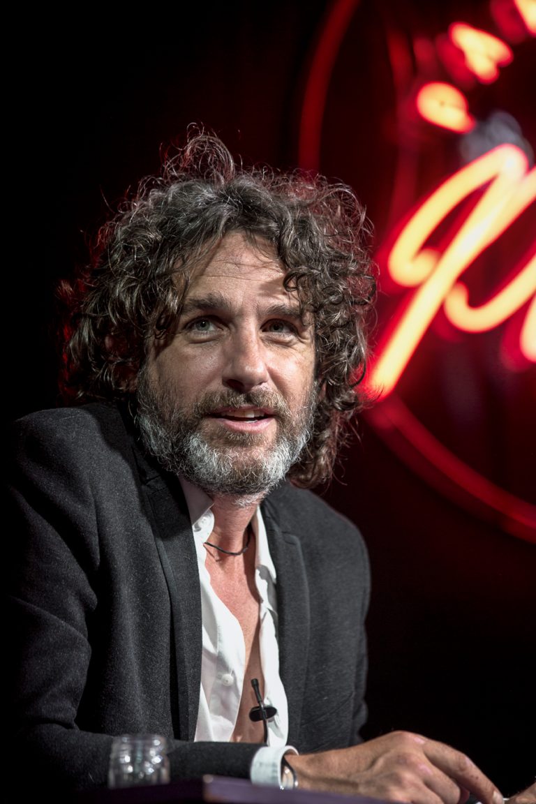 Tom Stade seated in front of a red neon sign