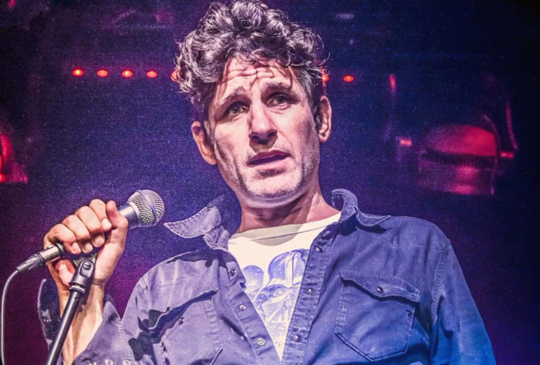 Tom Stade on stage holding a microphone, Live in Liverpool