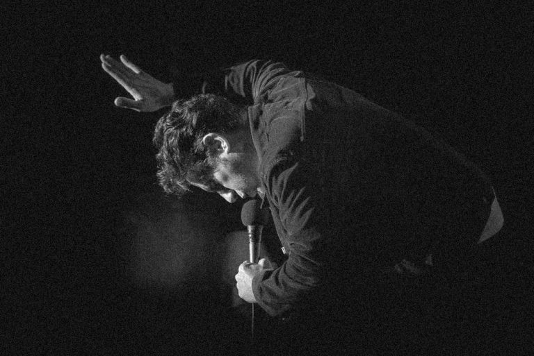 Tom Stade leaning over the mic on stage, black and white